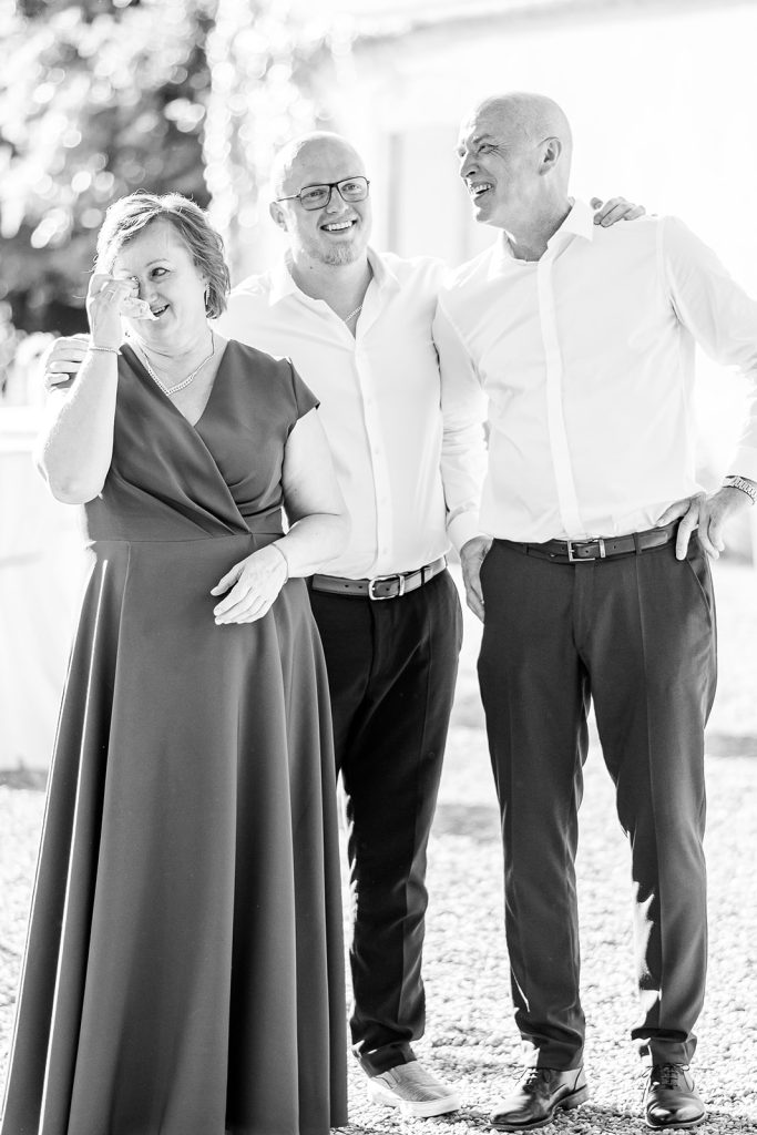 une famille papa, maman et fils tous d&eacute;j&agrave; adultes habill&eacute;s de mani&egrave;re &eacute;l&eacute;gante, la femme pleure elle a un mouchoir dans la main