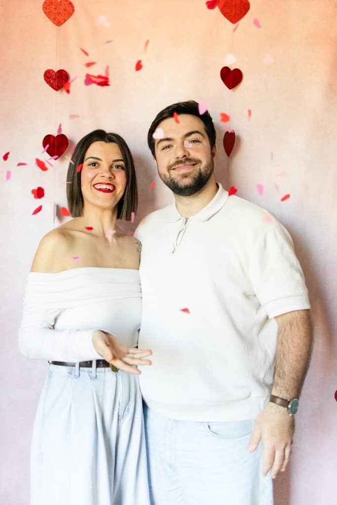 un couple qui jete les confettis en forme de coeurs derri&egrave;re avec un fond rose pour la saint valentin