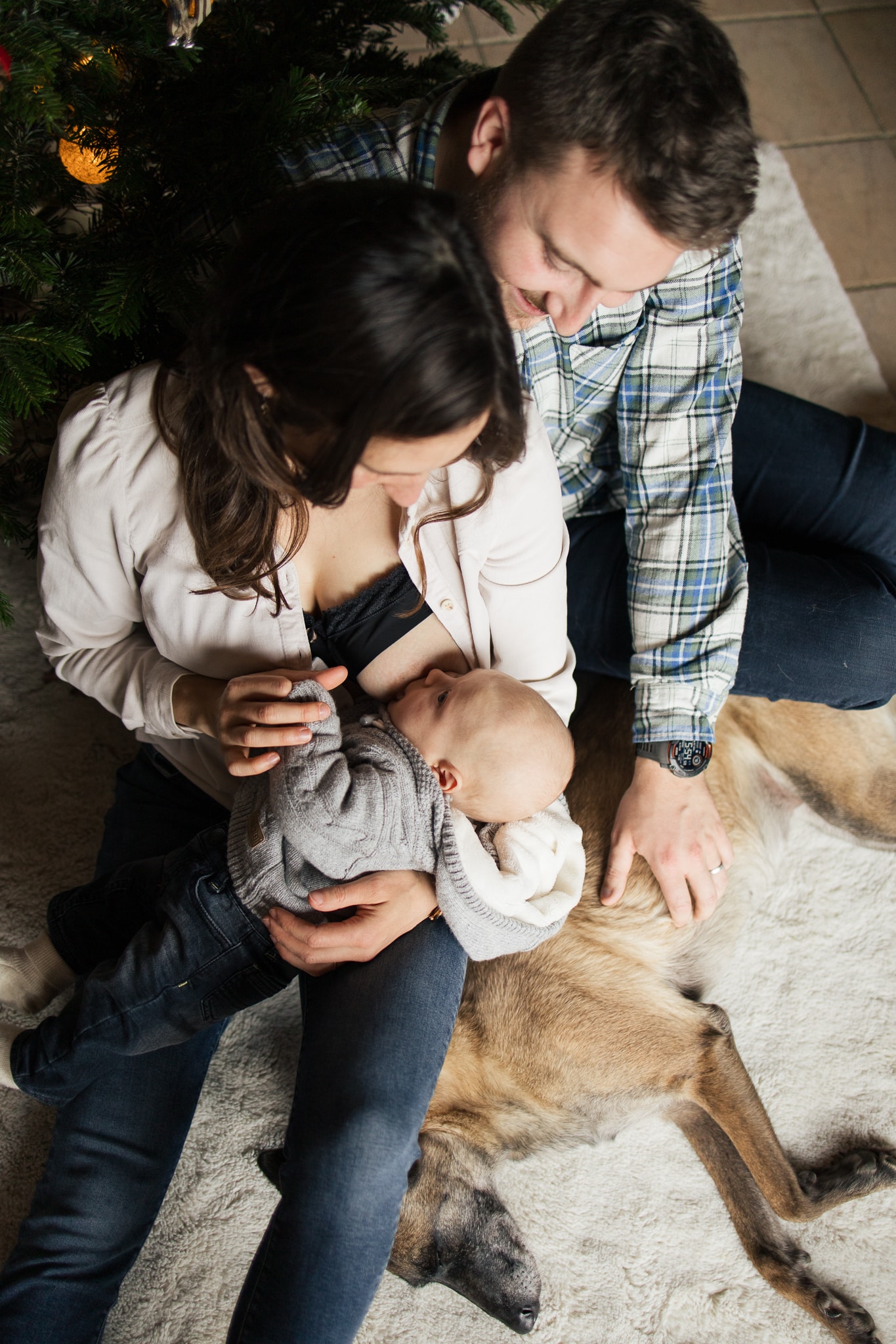 un couple assis parterre avec leur chien et leur b&eacute;b&eacute; qui est en train de manger, la femme l'allaite