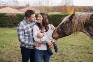 un couple avec un b&eacute;b&eacute; qui est dans les bras de la maman, &agrave; droite il y a un cheval qui regarde le b&eacute;b&eacute;