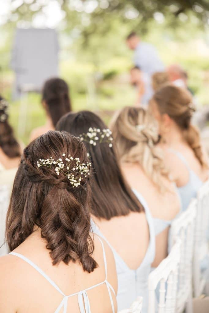 trois t&ecirc;tes de filles qu'on voit de derri&egrave;re avec des d&eacute;corations florales dans les cheveux