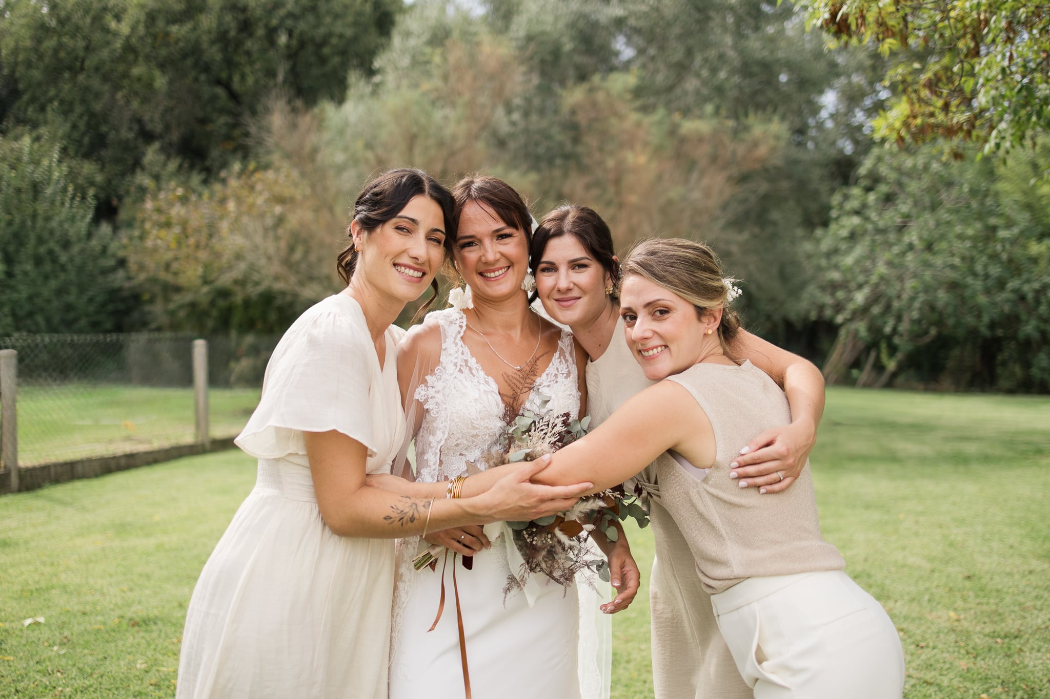4 filles une au milieu en robe de mariée se font un calin