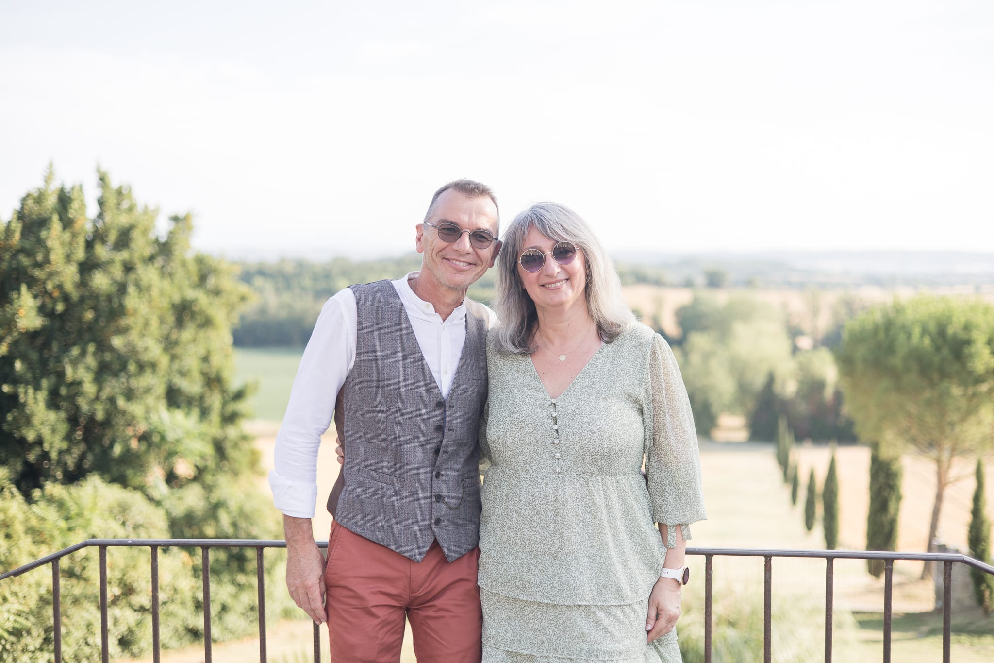 un couple devant une vue sue une hall&eacute;e et un champs avec des lunettes de soleil